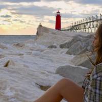 Photograph featuring female-presenting figure contemplating the horizon at a beach-like setting